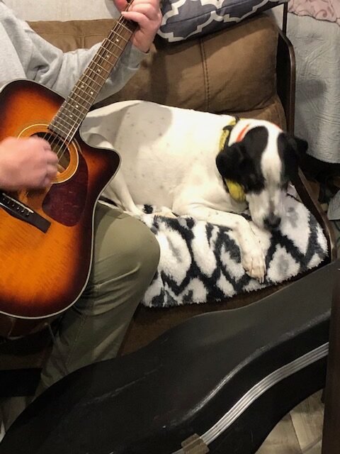 Dean playing guitar with dog